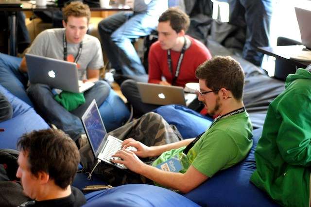 men with laptops huddled together at tech networking event
