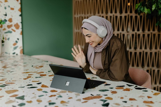 hybrid event services woman smiling and waving at laptop during hybrid events production