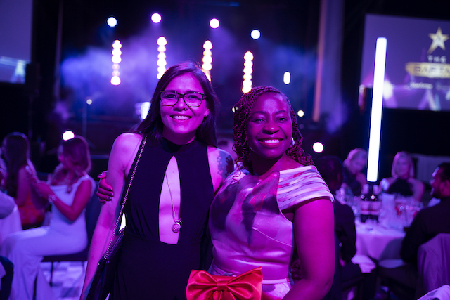 bluearrow-cost of venue image Two women smiling inside lively event venue for blog called, how much does it cost to rent out a venue in Manchester?